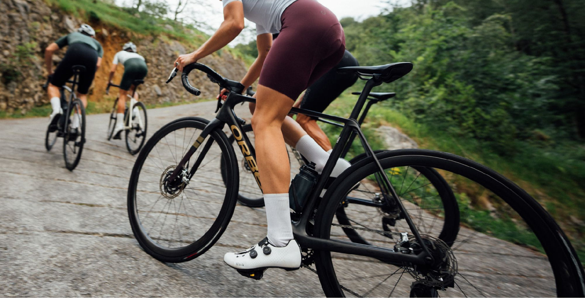 A group of cyclists riding the Orbea Orca Road bike up a hill. 