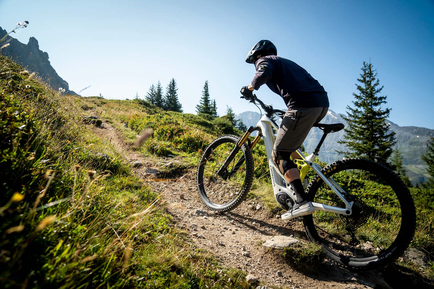 A man riding an Orba Wild Mountain bike with white paint on a trail in the mountains.