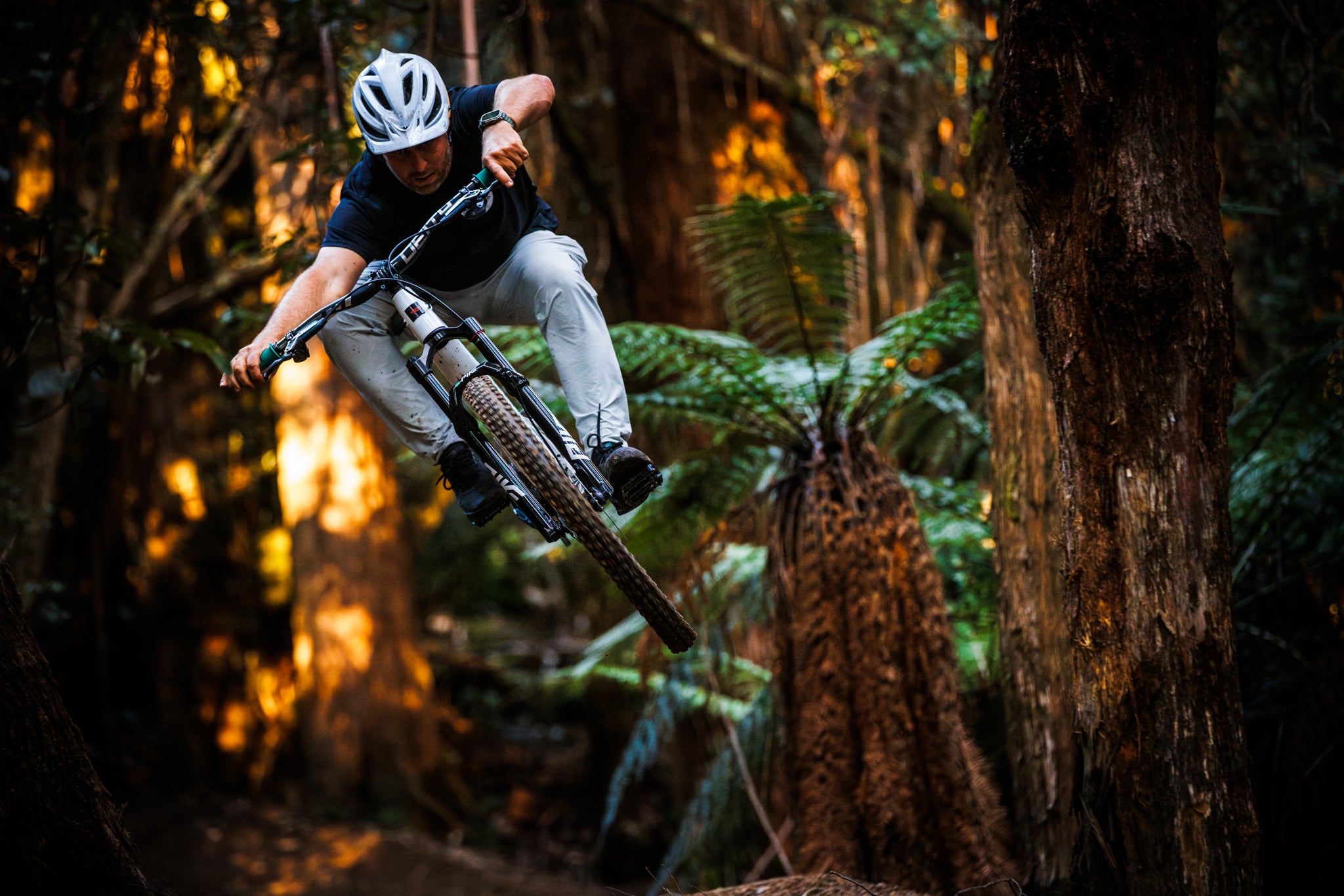 An action shot of a man riding a Santa Cruz Tallboy on a forest trail, navigating through loose rocks and uneven terrain, demonstrating the bike’s stability and performance in tough conditions, available at Contender Bicycles.