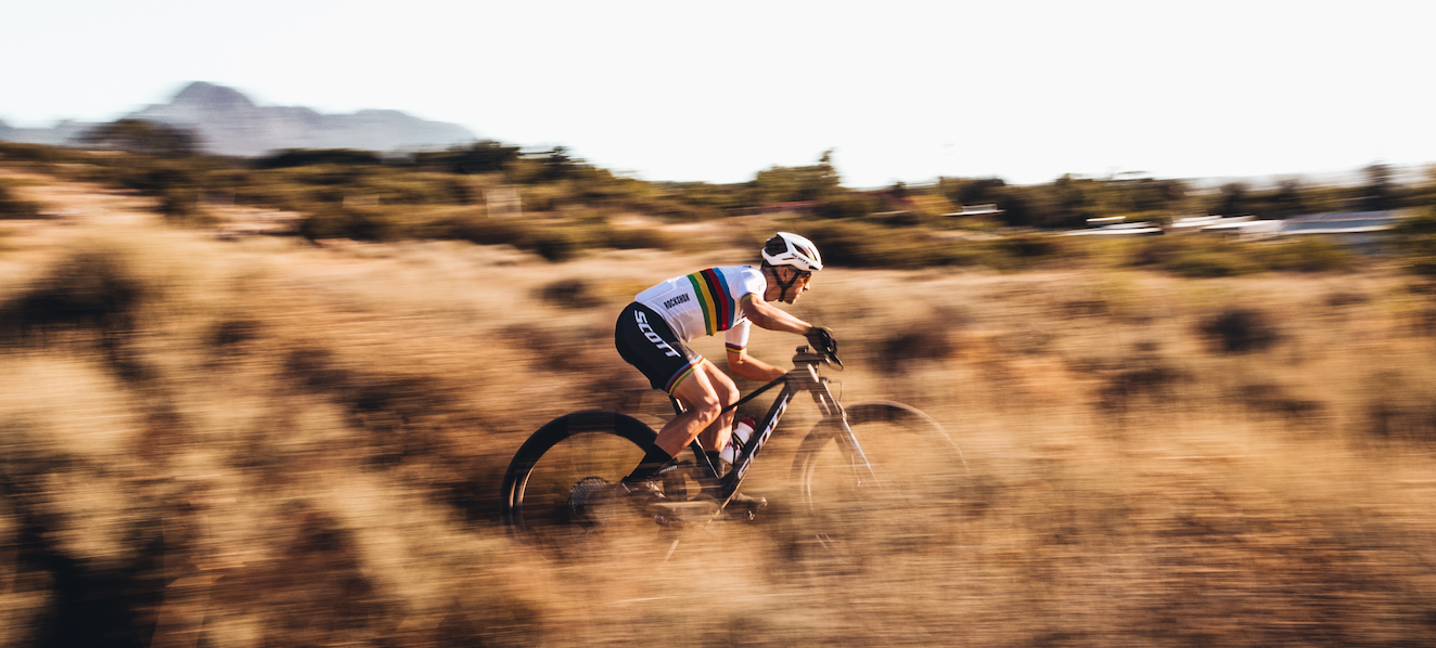 A man riding the Scott Spark RC Mountain bike in tall grass. 