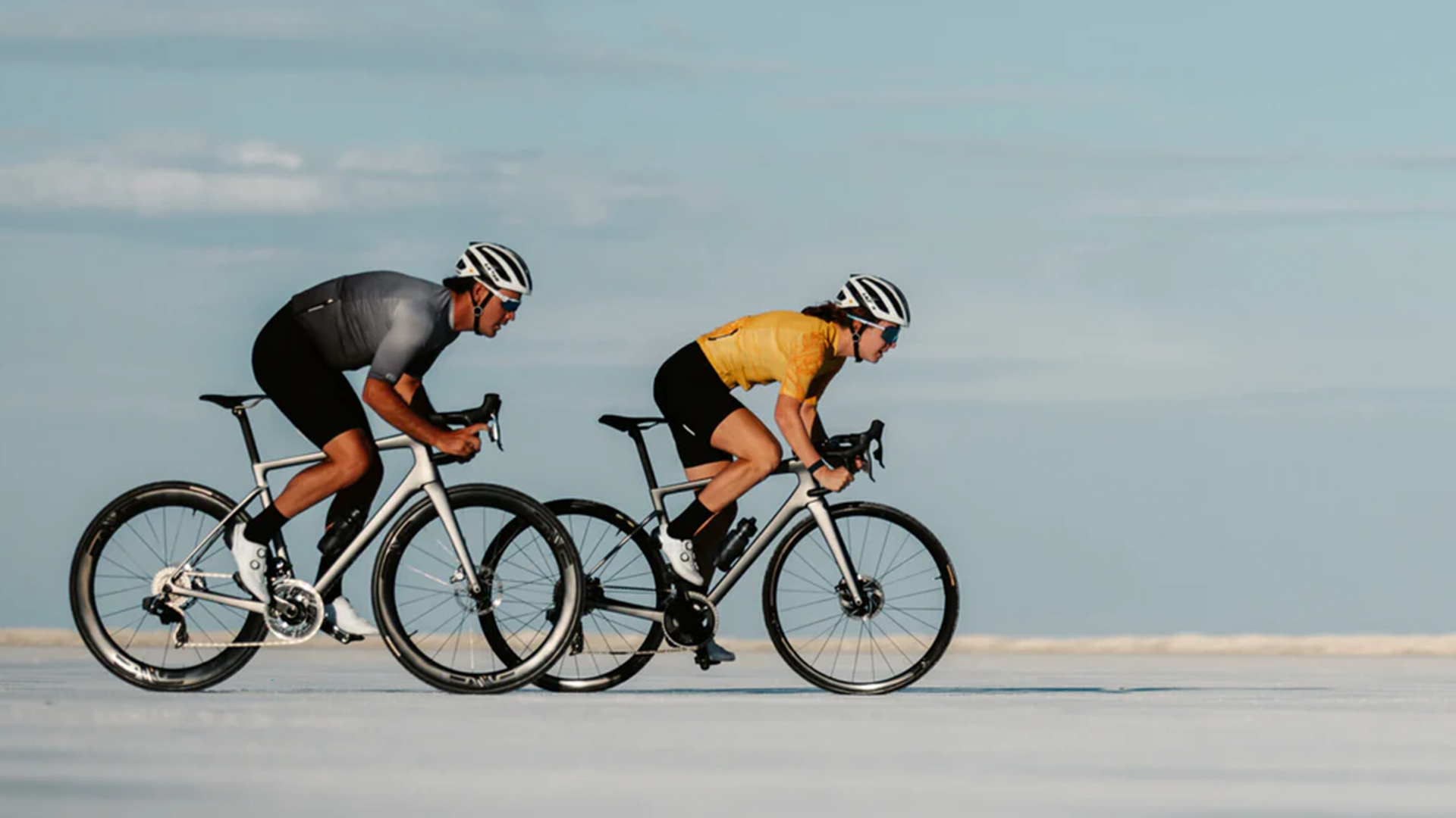 Two men riding ENVE bikes on a wide open road with a blue sky in the background