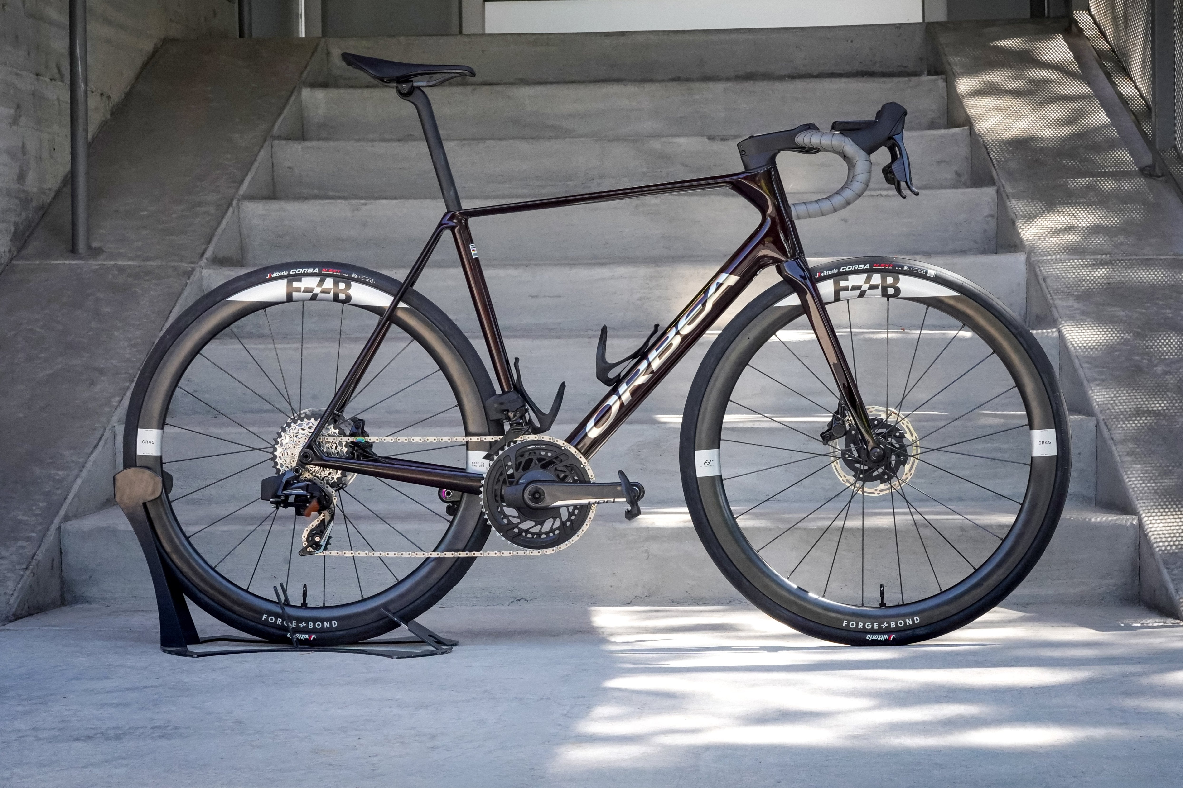 An Orbea Orca Aero Road bike staged in front of some cement Stairs.