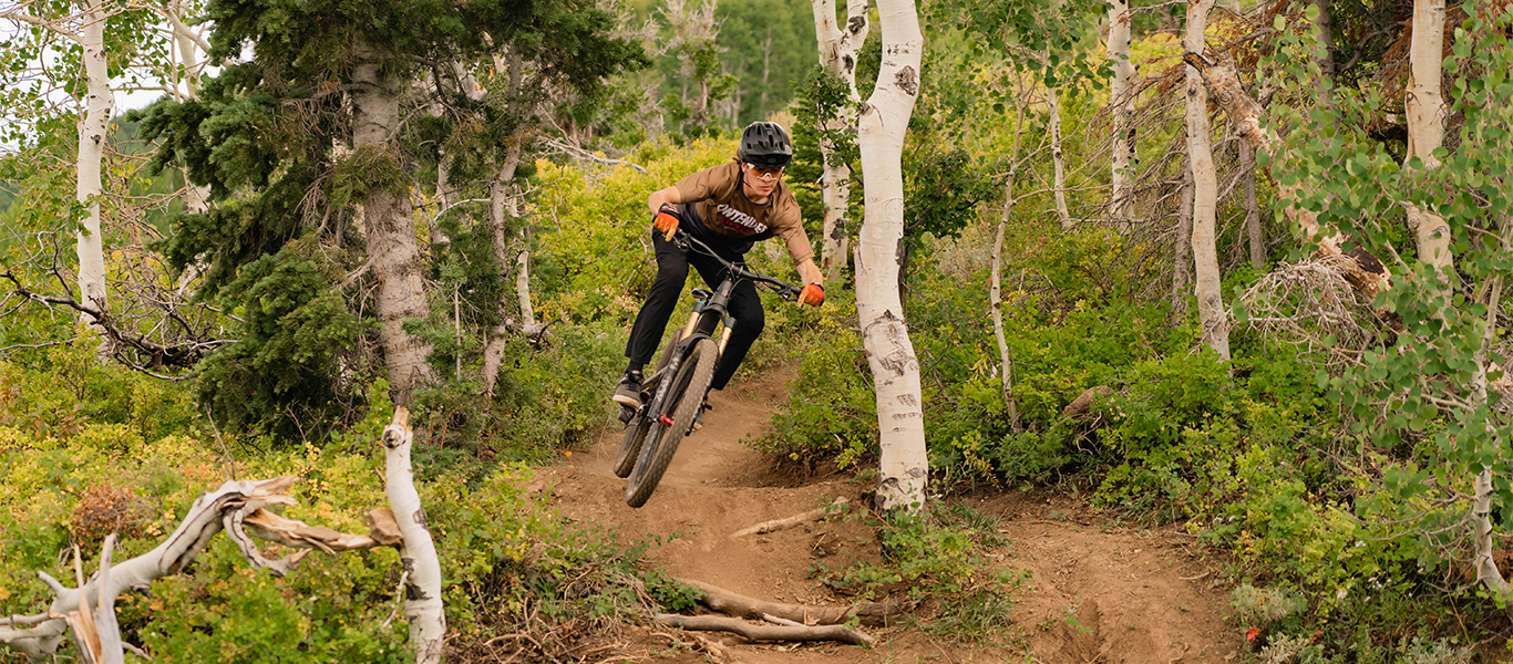 a man riding a mountain bike in the forest, he is jumping in the air