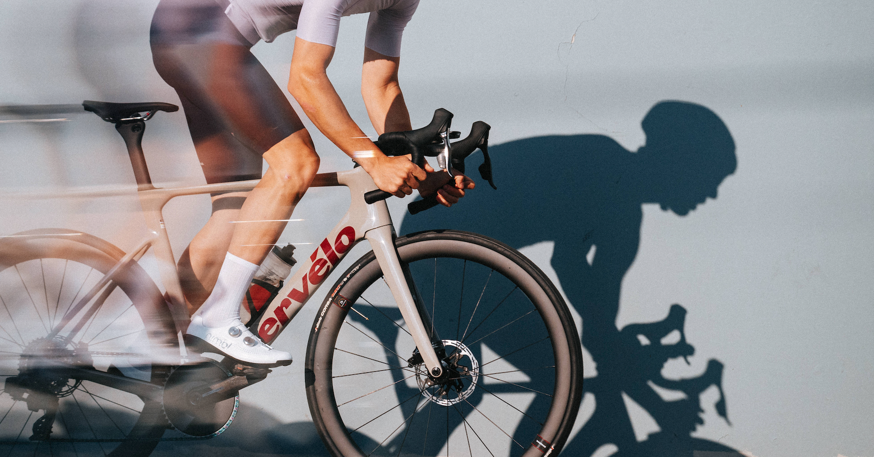 a man riding a cervelo s5 road bicycle that is gray with red text